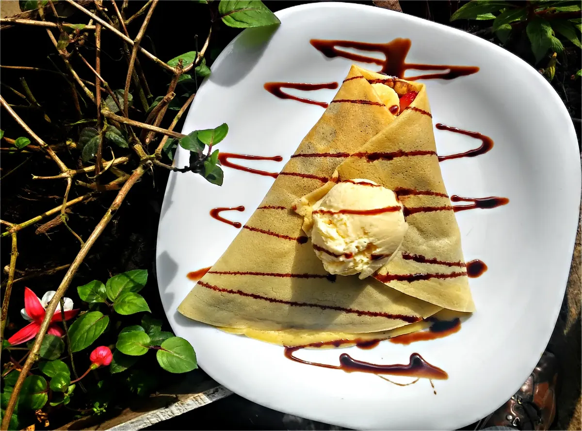 パリの外での、香り高いフランスのクレープにヴァニラアイスクリームとチョコレートドレッジがかけられた写真